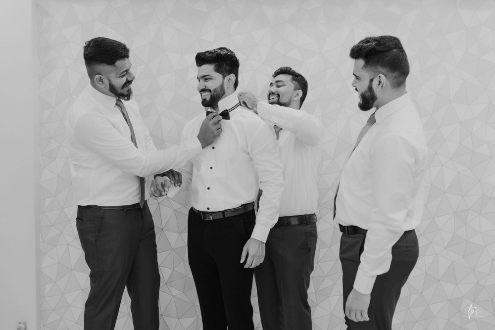 Black and white photo of groomsmen laughing and interacting before wedding ceremony.