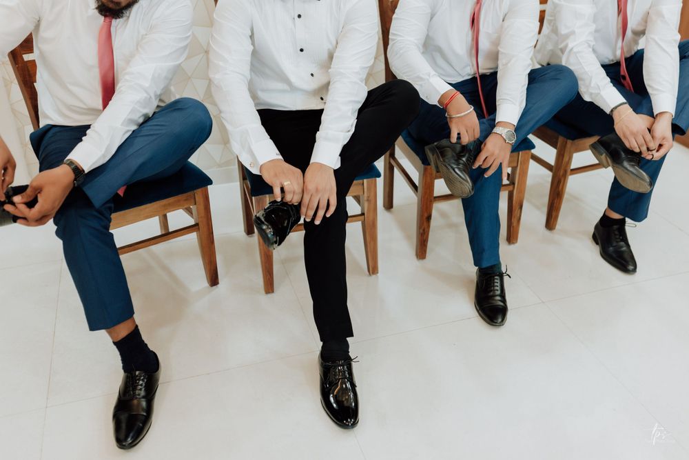 Wedding party members in white dress shirts and blue jeans sit casually displaying their formal footwear.