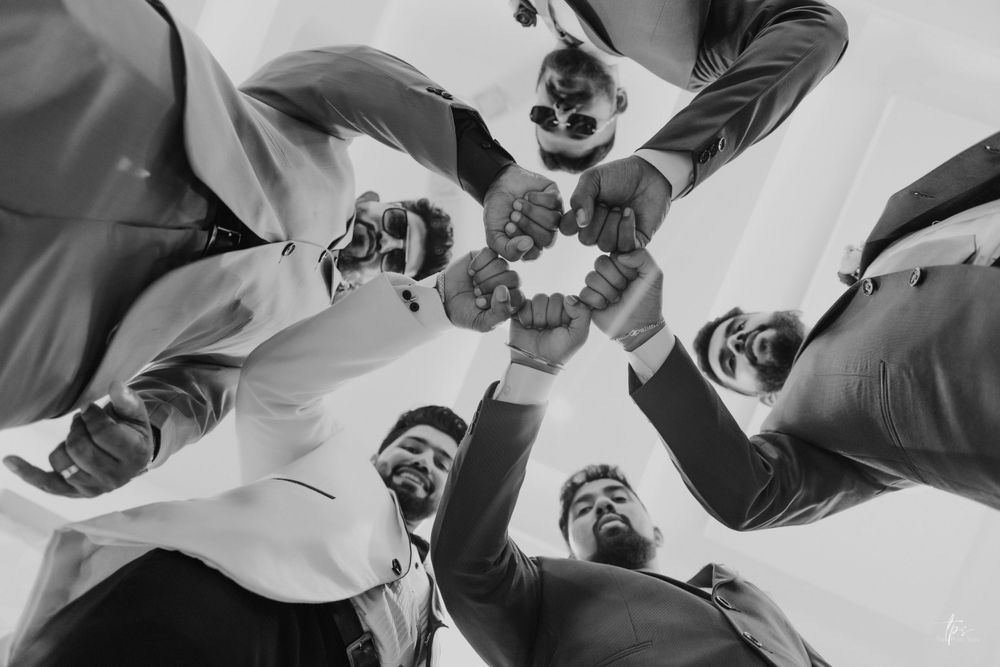Wedding party members form a circle viewed from below in black and white photography.