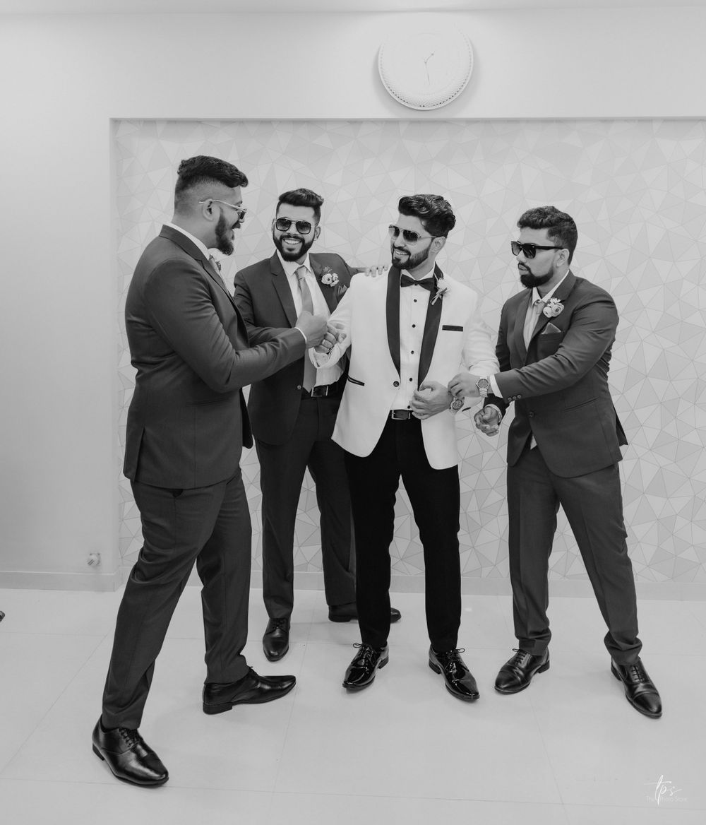 Groomsmen in formal attire share a candid moment during wedding preparations.