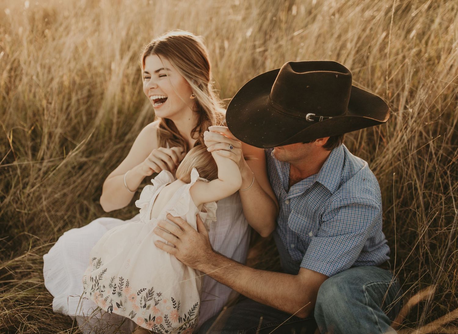 A candid couples photoshoot in a golden wheat field at sunset.