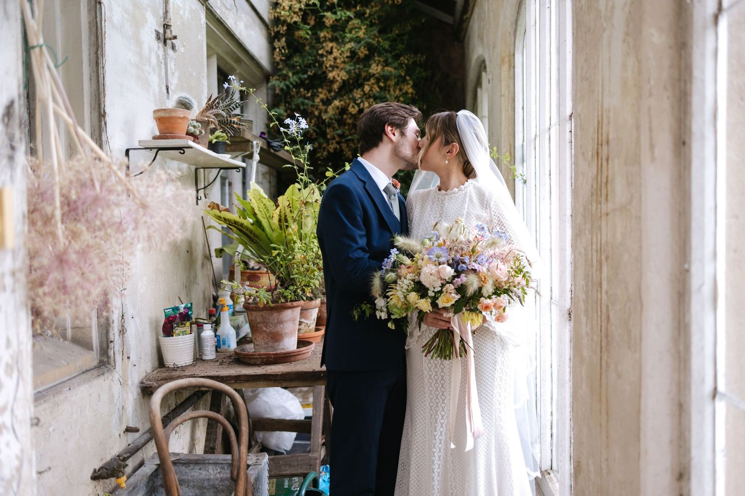 Romantic wedding couple embracing on rustic porch decorated with potted plants and floral arrangements.
Holme pierrepont hall