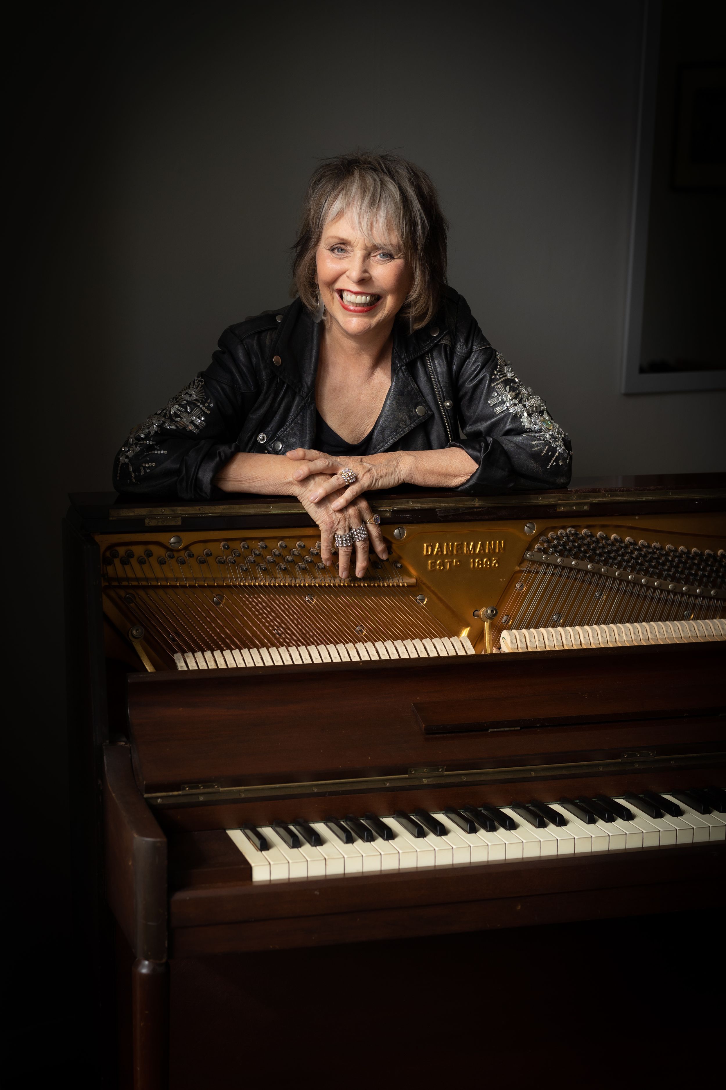 A beautiful portrait of pianist Jan Preston standing behind a piano
