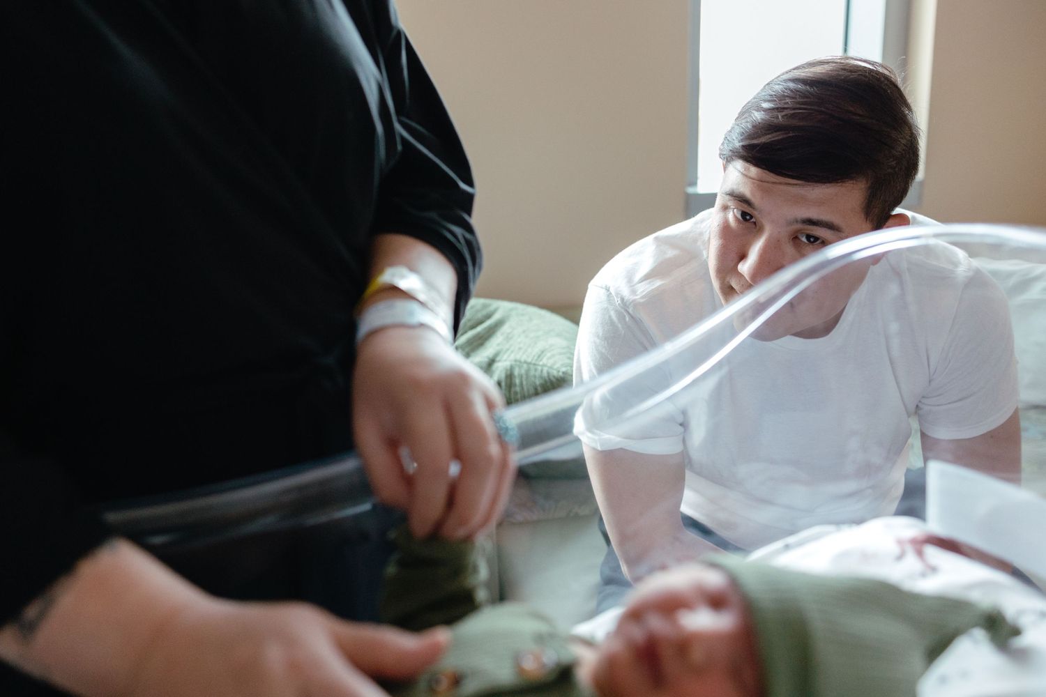 Medical professional attending to someone in hospital room with gentle care.