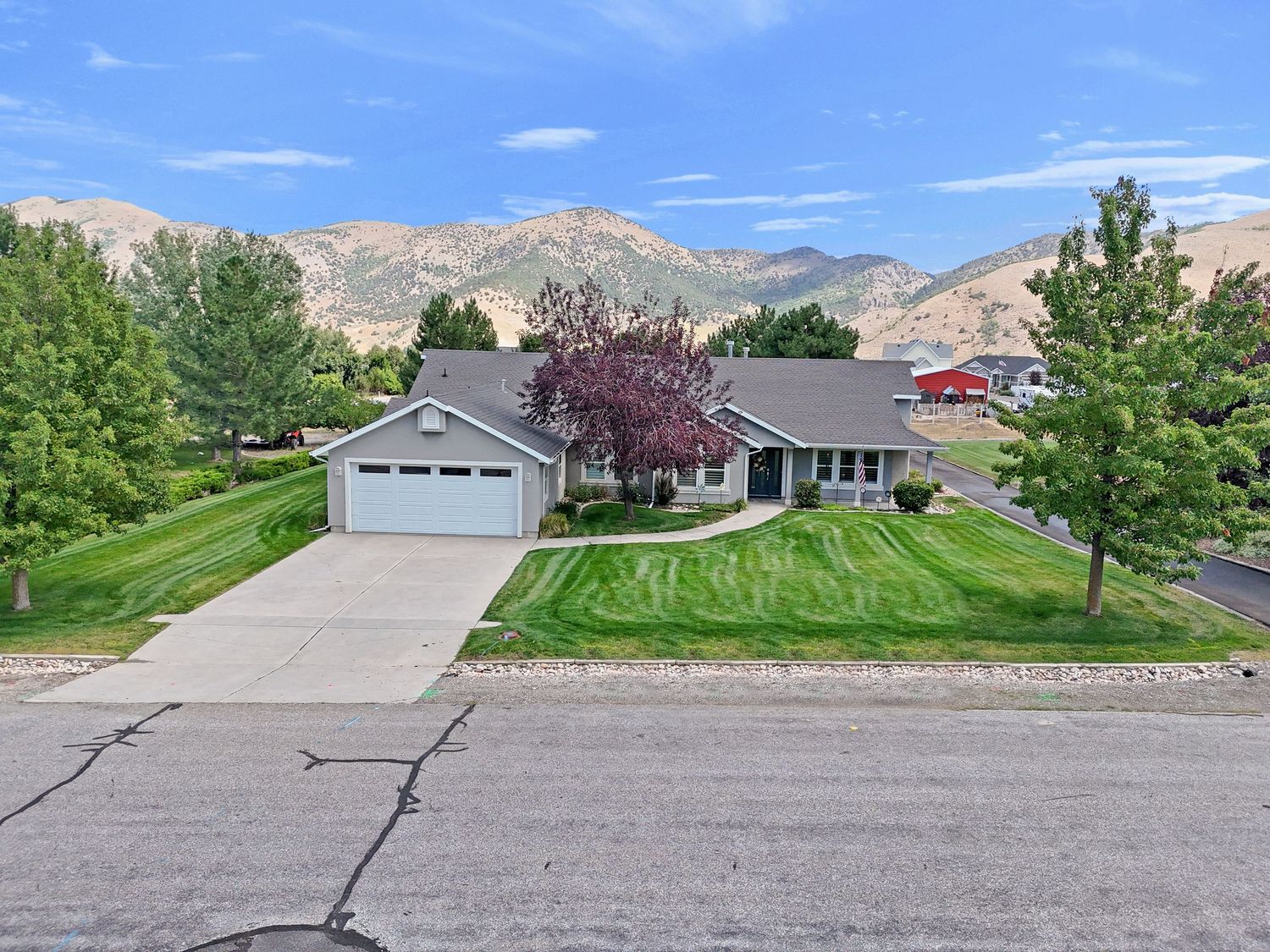 Ranch-style home with two-car garage, green lawn, and stunning mountain views.