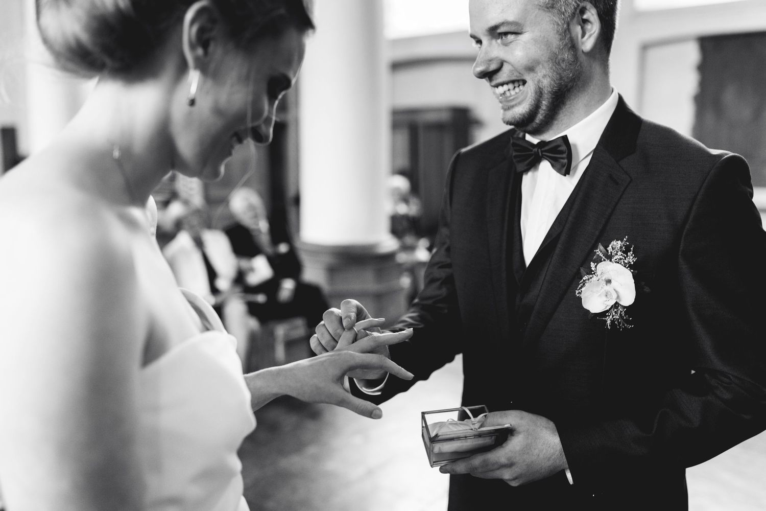 Couple sharing a moment during ring exchange at formal wedding ceremony.