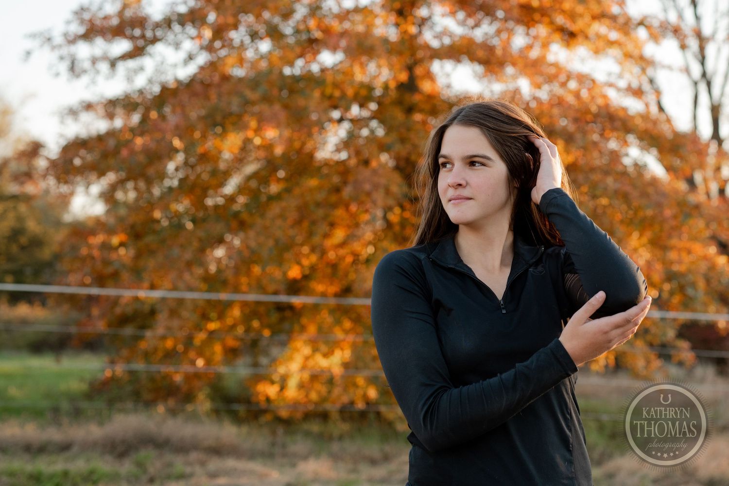 Portrait against bright orange autumn tree with arms crossed.