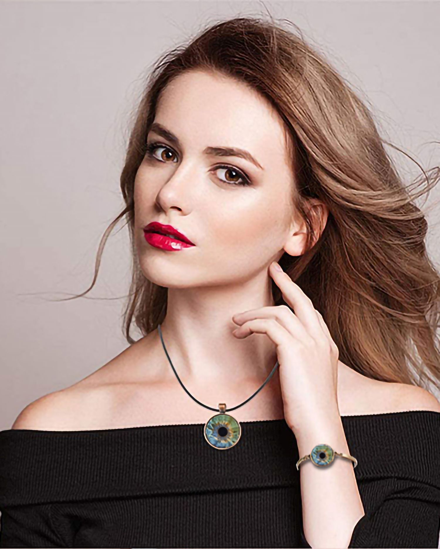 Fashion model wearing black off-shoulder top with eye-design jewelry.