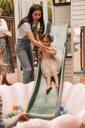 A playful moment on a green slide with pink inflatable decorations and colorful balls.