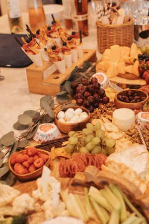 An elegant charcuterie spread with cheeses, grapes, and appetizers arranged on a wooden table.