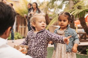 Children playing together in a garden with palm trees.