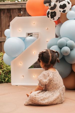 Party scene with balloon arch featuring cow print and light-up number display.