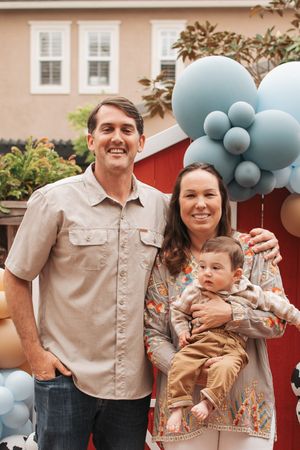 Party scene with rustic barn backdrop and festive balloon arch in blue and orange.