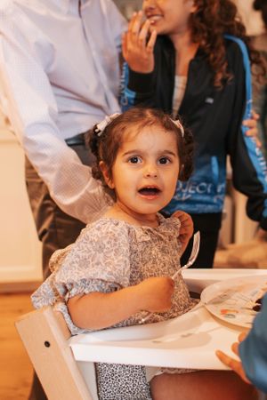 Young child in sparkly dress sitting at table during celebration.
