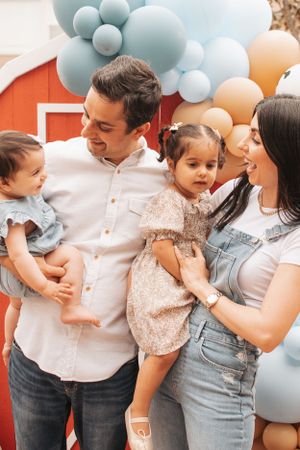 Happy gathering in front of barn-themed party backdrop with balloon decorations.