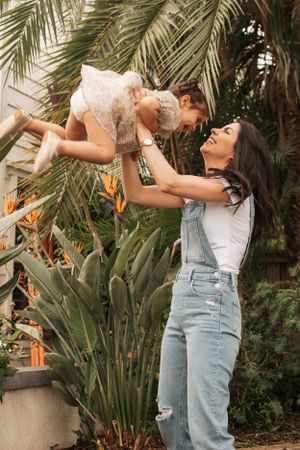A joyful moment captured in a garden setting with palm trees and tropical plants.
