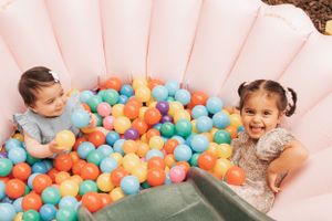 Colorful ball pit filled with orange, blue, and beige balloons creates a festive party atmosphere.