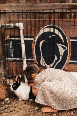 A black and white rabbit hutch with decorative design against a wooden wall.
