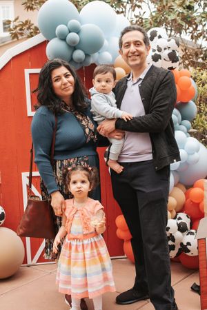 Farm-themed party decoration with red barn backdrop and blue and orange balloon garland.