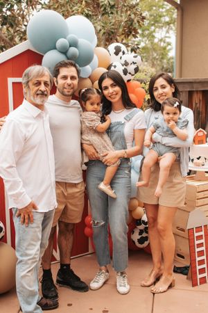 A family gathering outdoors with decorative balloons featuring soccer ball patterns and pastel colors.