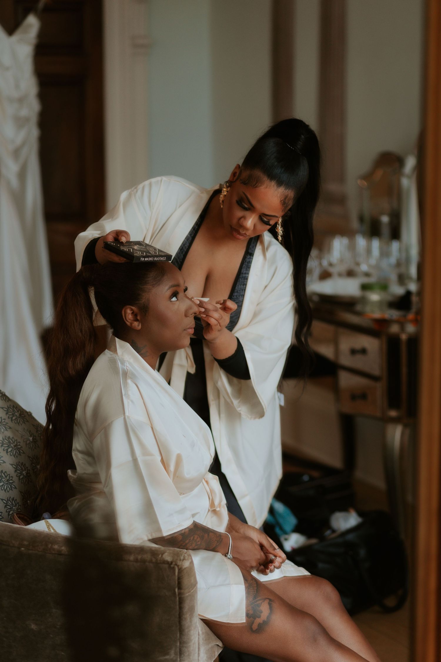 A makeup artist styles a client's hair during wedding preparation in a getting-ready room.