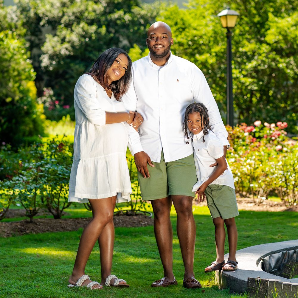 Family in coordinated white and green outfits poses together in park setting.