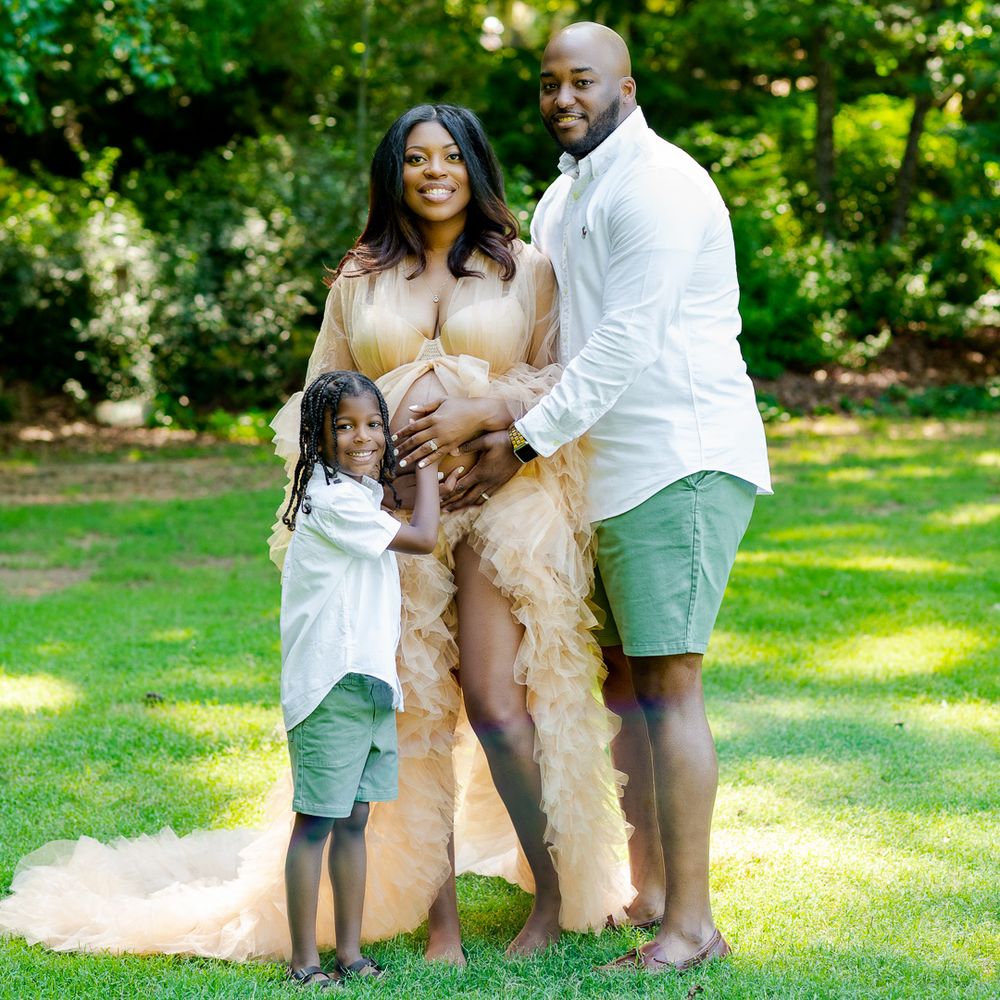 Family in white and neutral tones poses together in sunny garden setting.