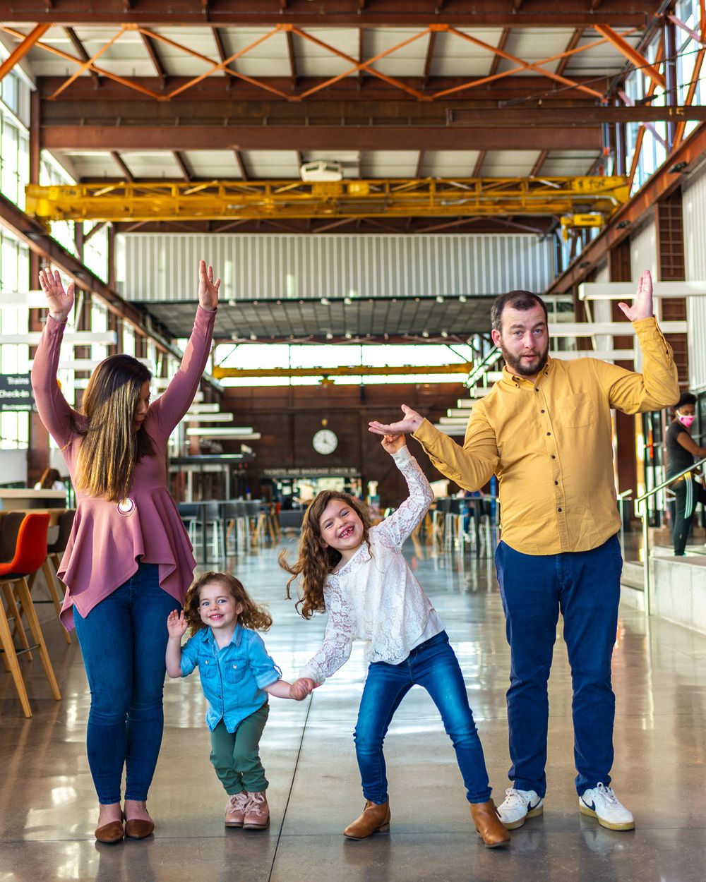 Family striking fun poses together in an industrial-style indoor space.