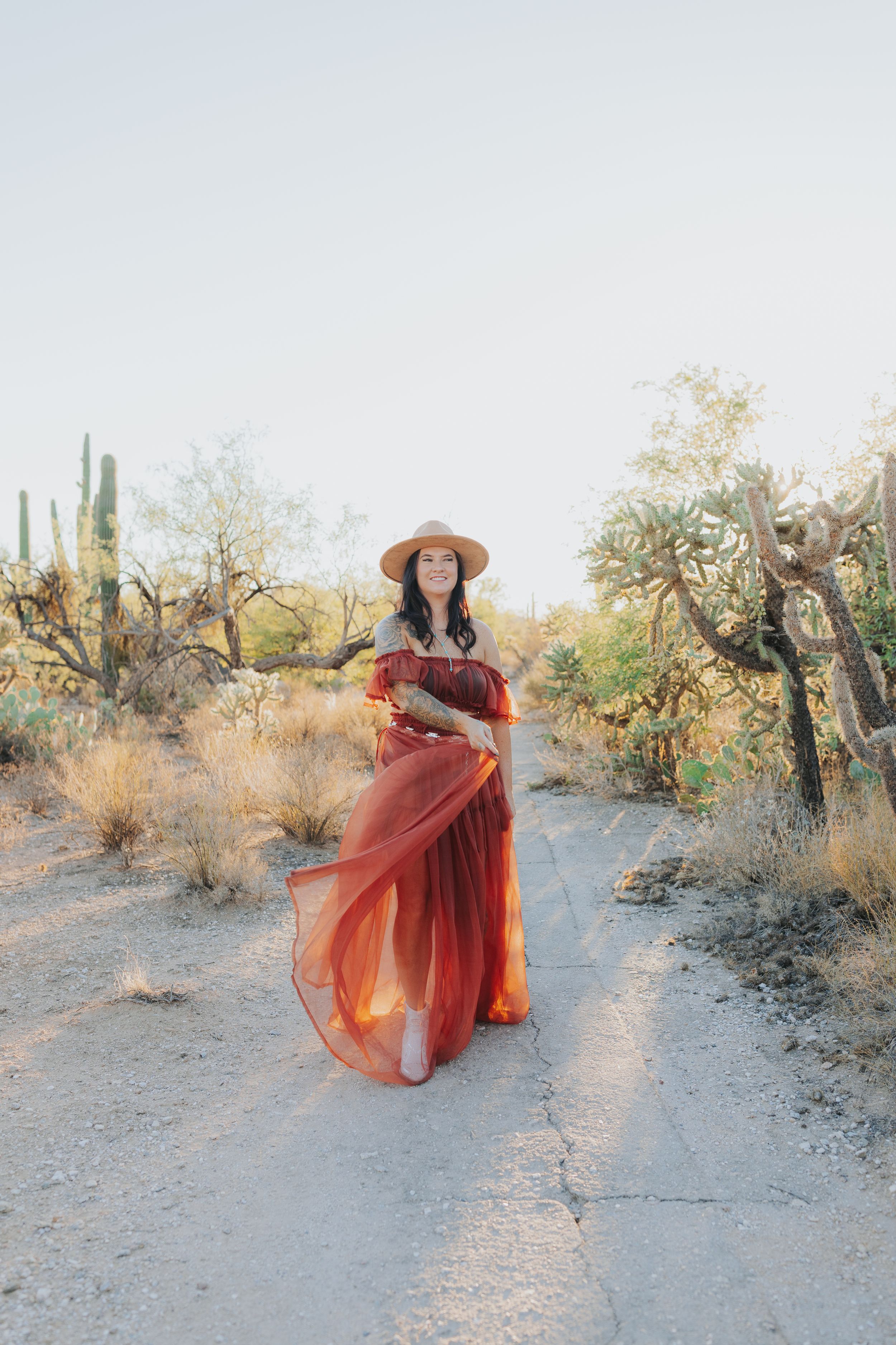 A flowing red dress creates movement in a desert landscape with saguaro cacti.