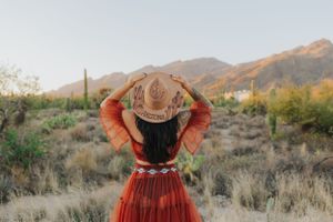 A rust-colored dress twirls dramatically against desert mountains and sage brush.