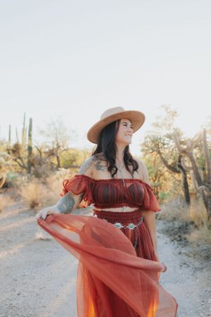 Desert fashion portrait with red off-shoulder dress and wide brim hat.