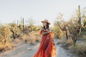 Desert fashion photography with flowing red dress among cacti and desert flora.