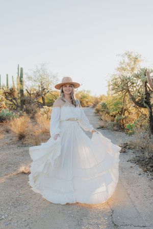 A white dress twirls gracefully on a desert path during golden hour.