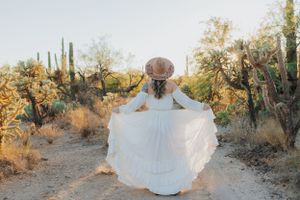 A flowing white dress twirls gracefully against a desert landscape with saguaro cacti and golden sunlight.