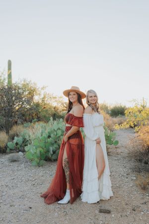 Two flowing dresses, one white and one rust-colored, create movement in a desert landscape.