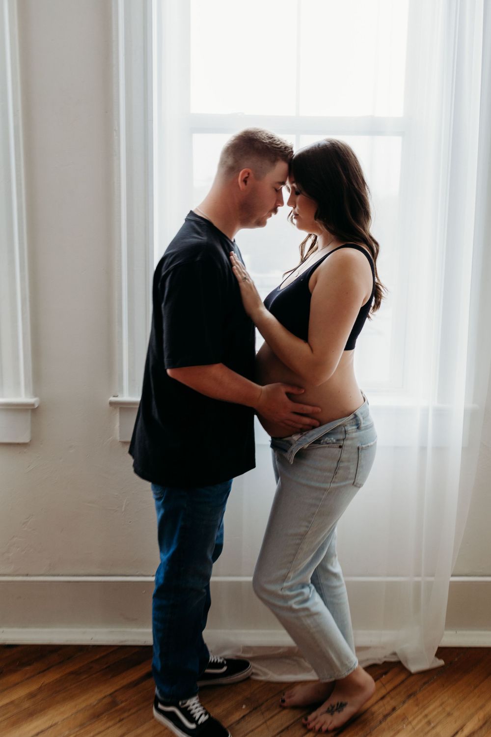 Intimate maternity portrait by window in natural light.