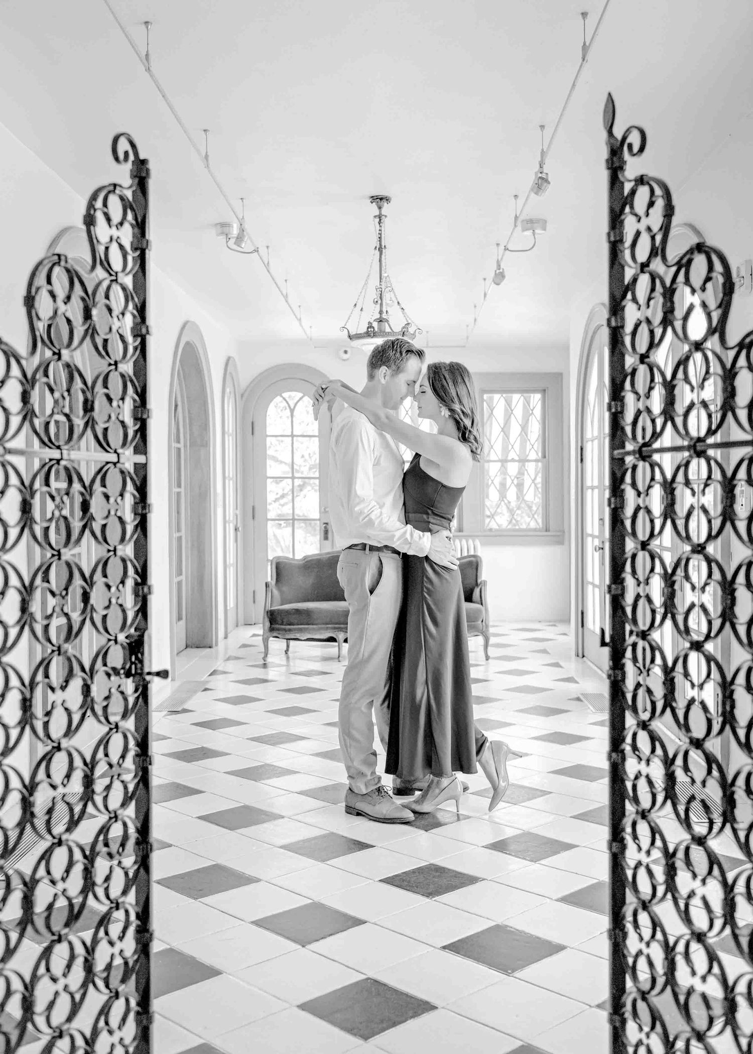 A romantic black and white portrait framed by decorative iron gates.