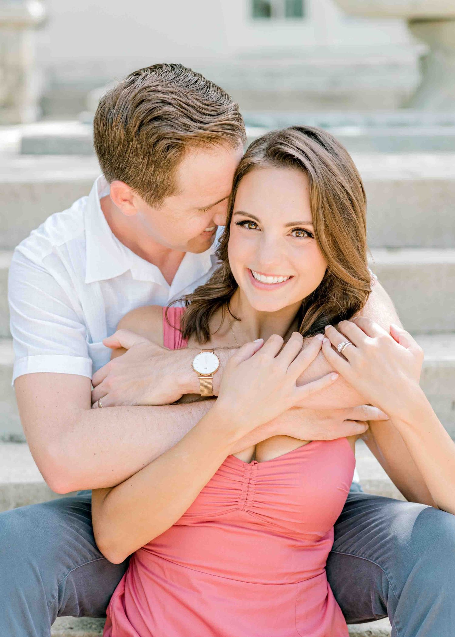 A couple shares an intimate moment together while sitting on stone steps.