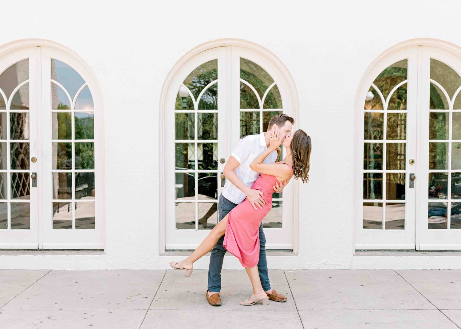 A romantic dance pose in front of arched windows at an elegant white building.