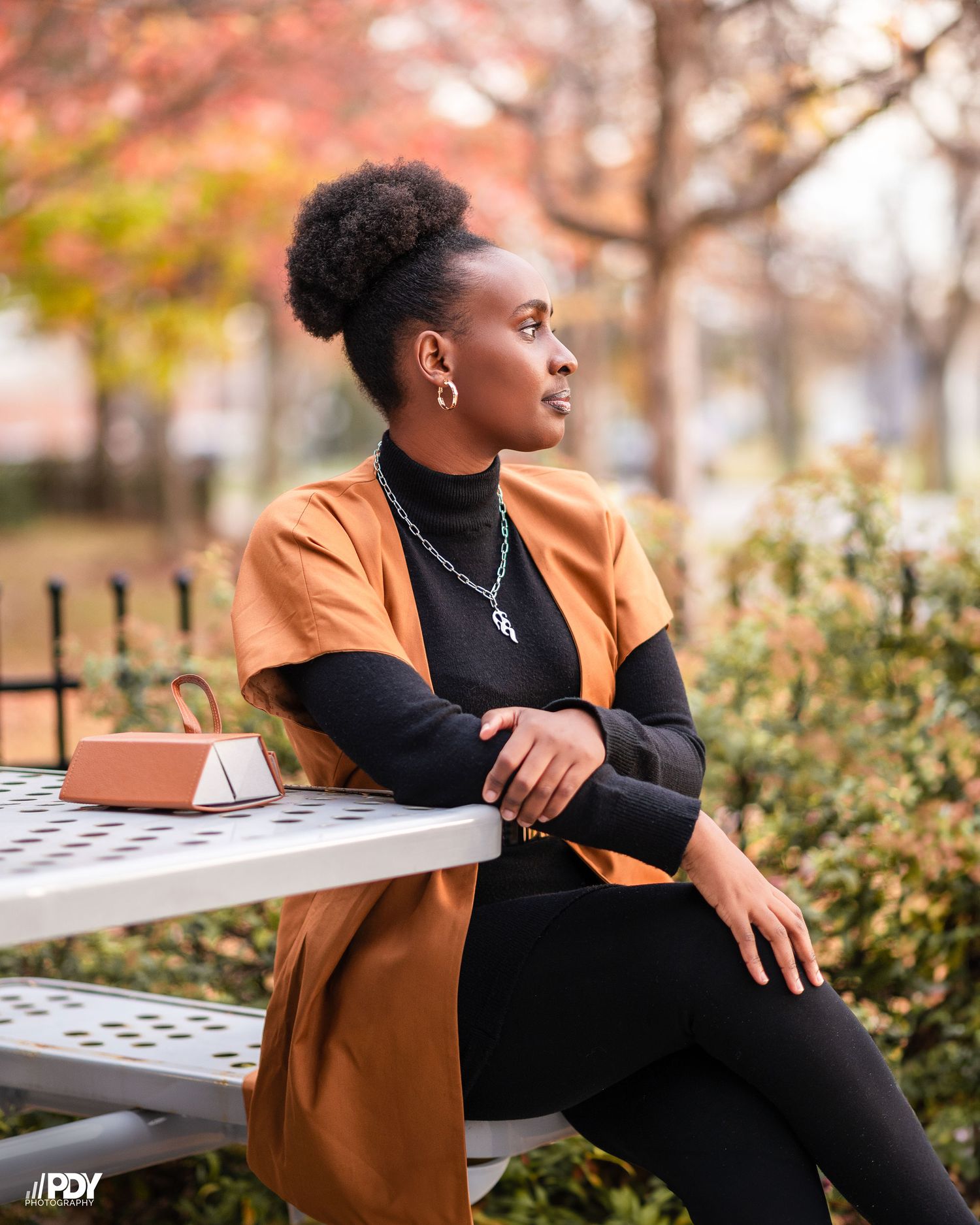 Casual fall portrait session on bench wearing orange jacket and black turtleneck.