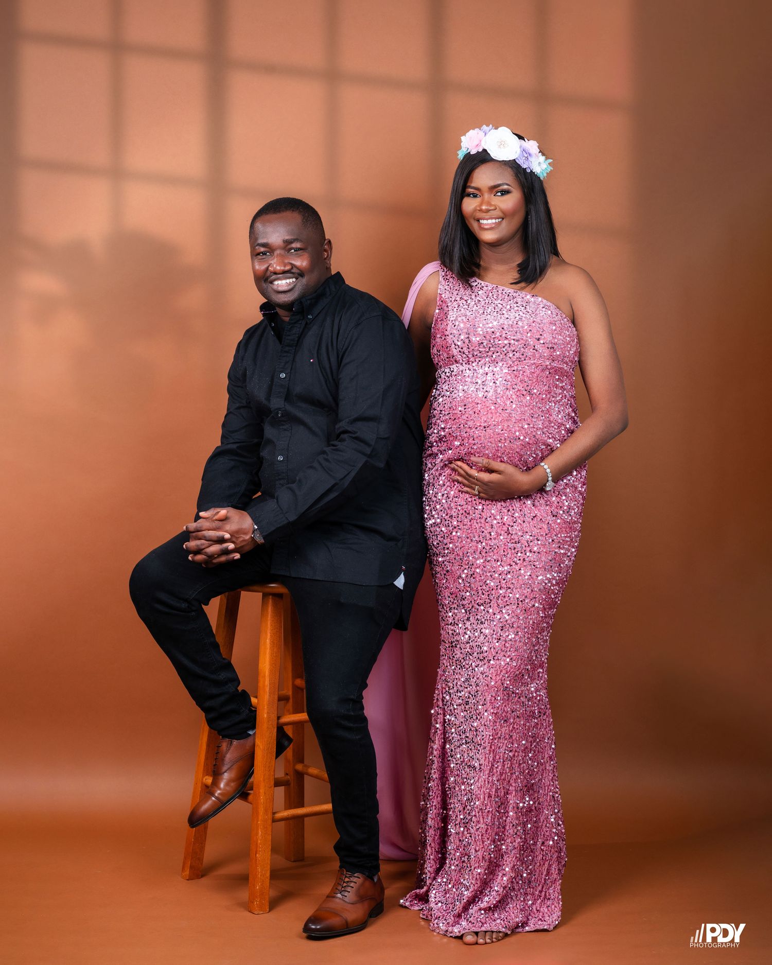 Maternity portrait session with a couple wearing formal attire - a pink sequined gown and black suit.