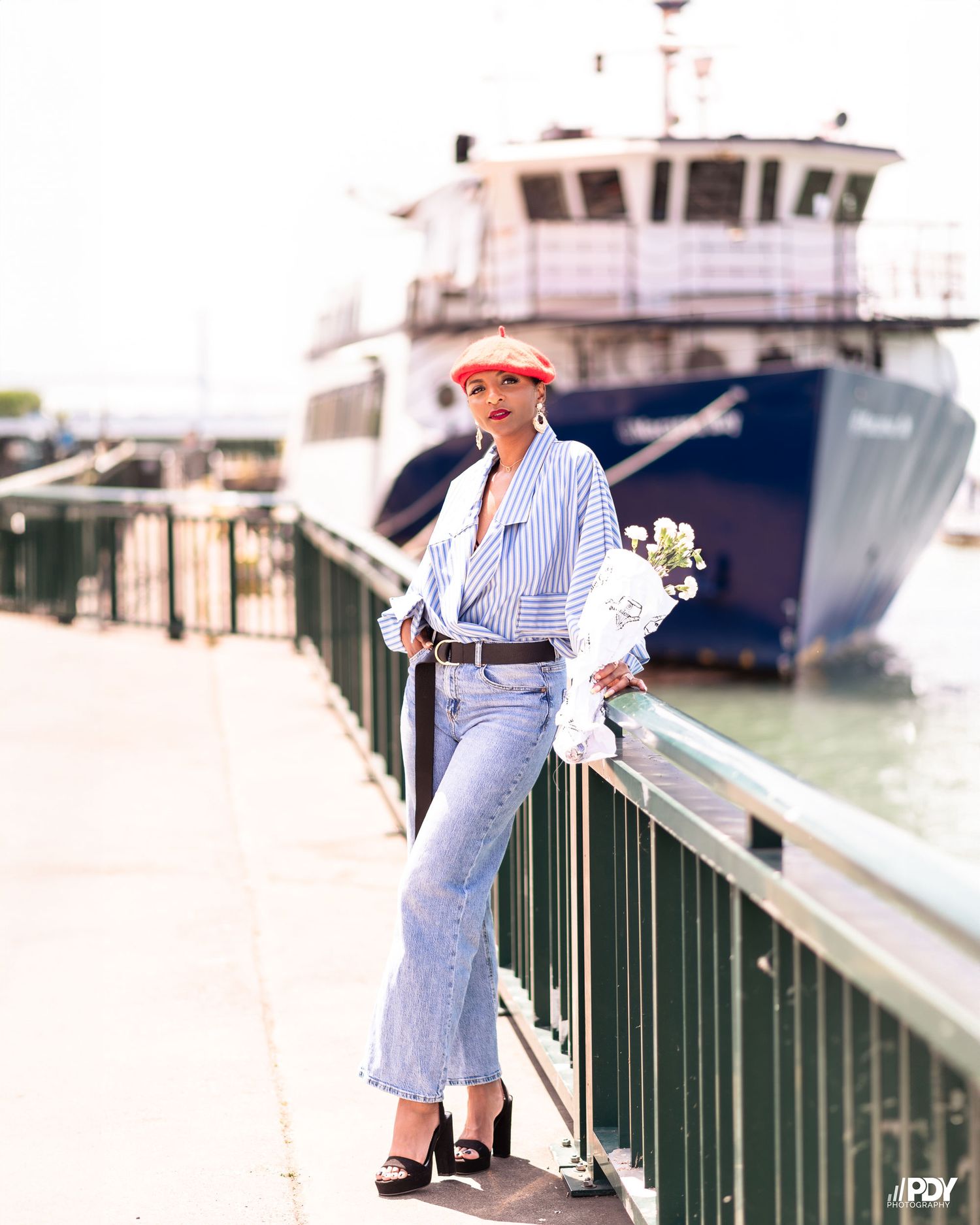 Stylish waterfront photography with striped shirt and denim near docked boats.