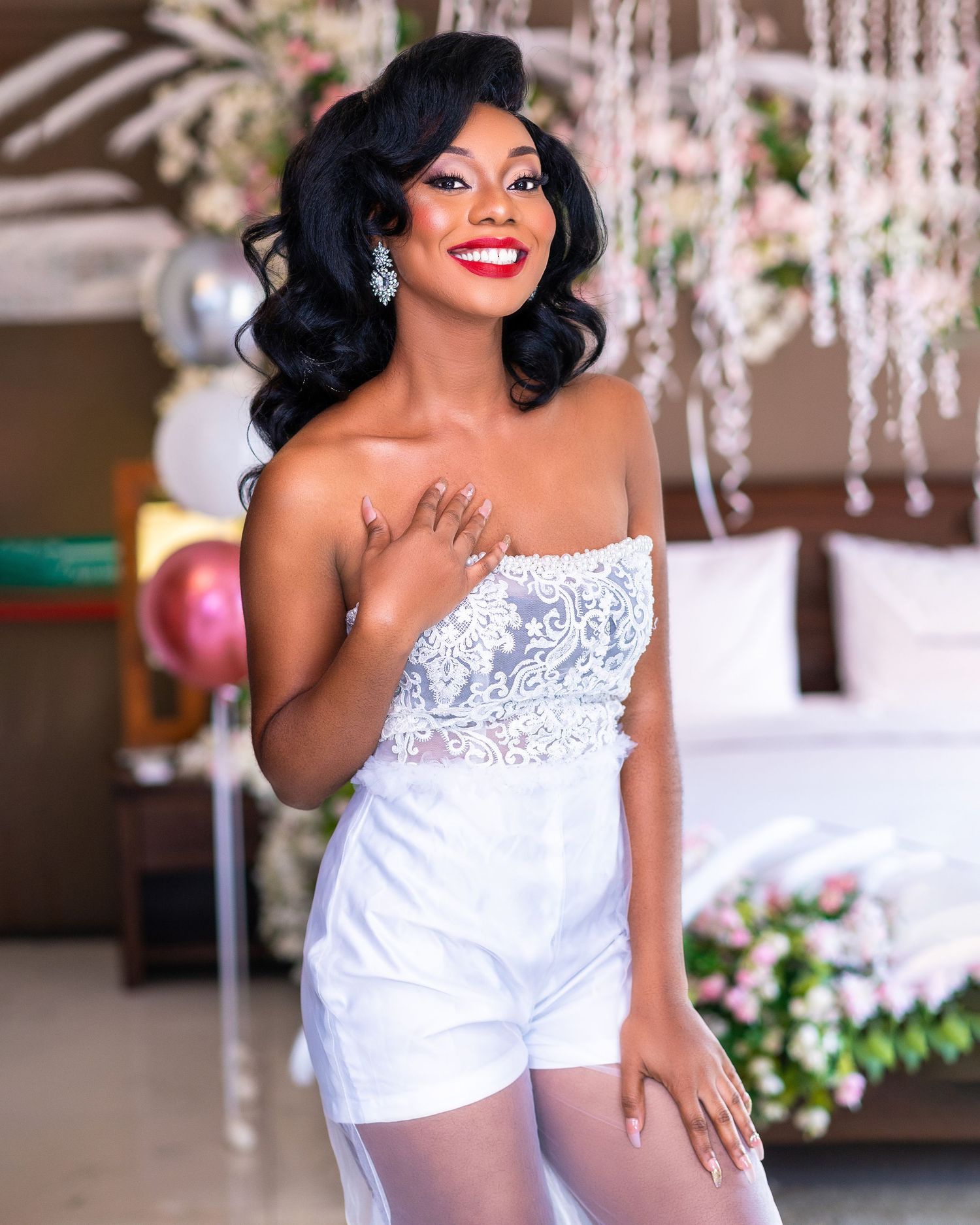 Bride in white beaded top poses elegantly under crystal chandelier decorations.