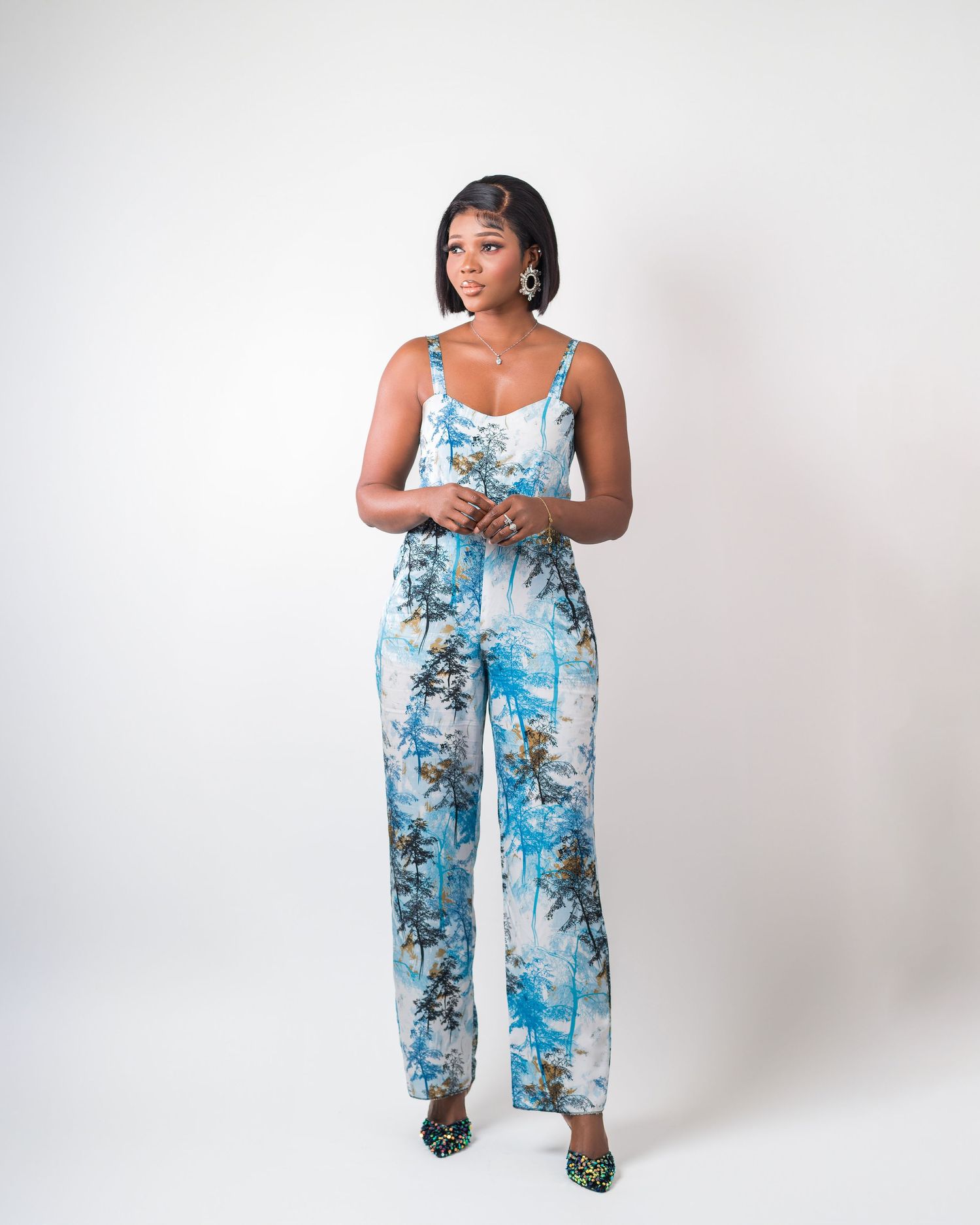 Blue floral print wide-leg jumpsuit styled against a white studio backdrop.