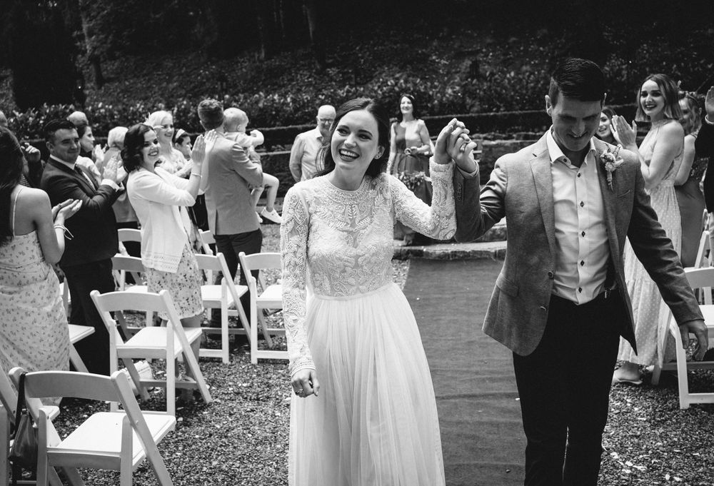 A joyful wedding celebration with dancing and white chairs in an outdoor garden venue.