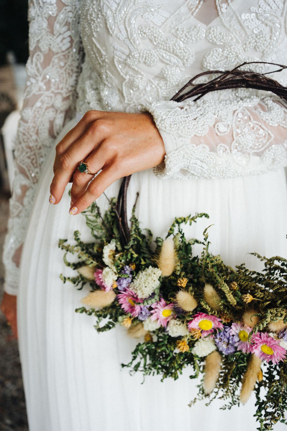 Close-up of an elegant bridal bouquet with wildflowers and a wedding ring on display.