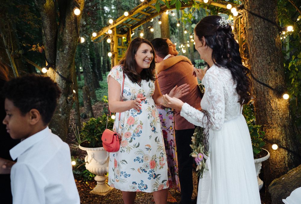 Wedding guests sharing congratulations at an outdoor forest reception with string lights.