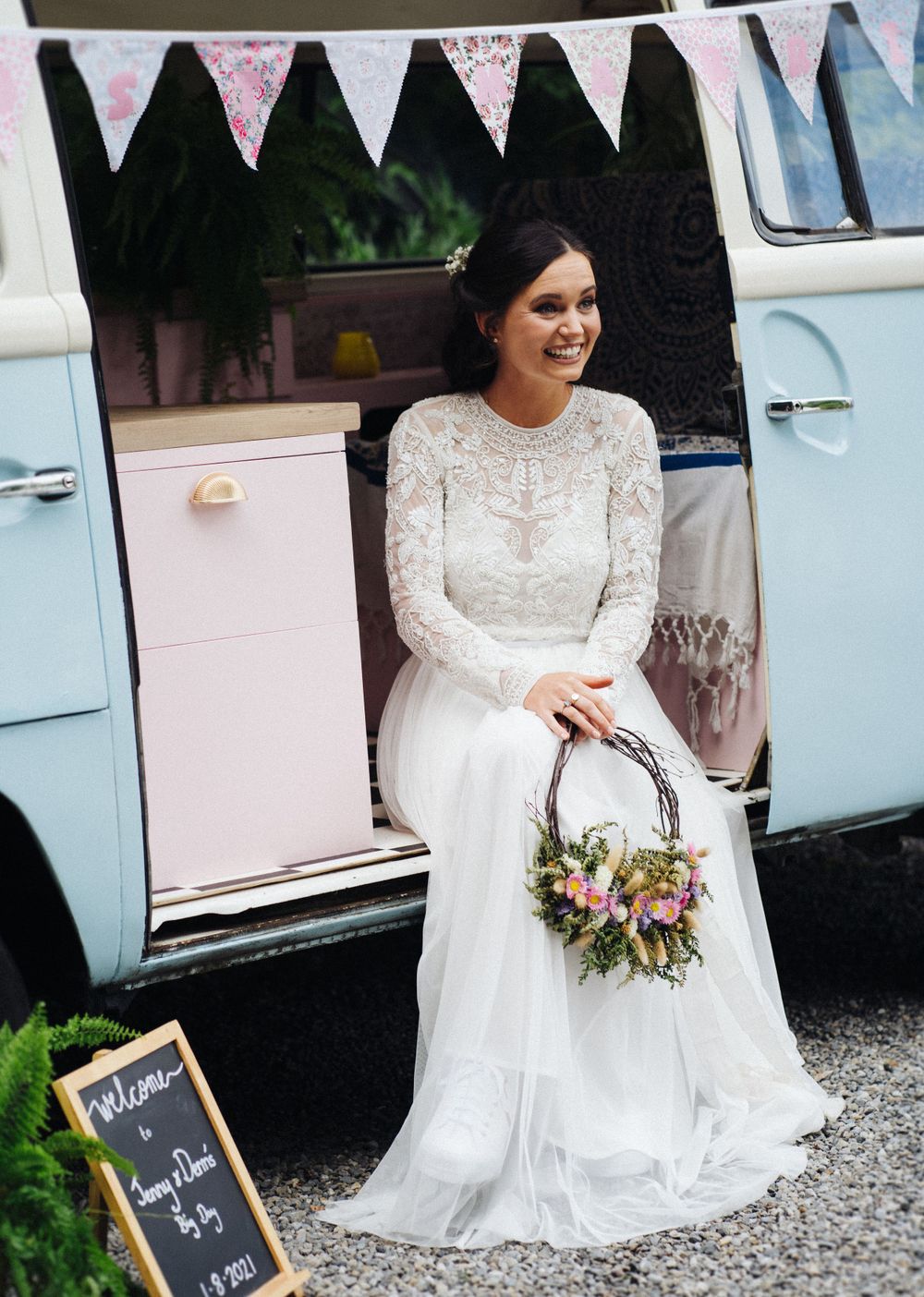 A vintage VW van decorated with bunting serves as charming wedding photo backdrop.