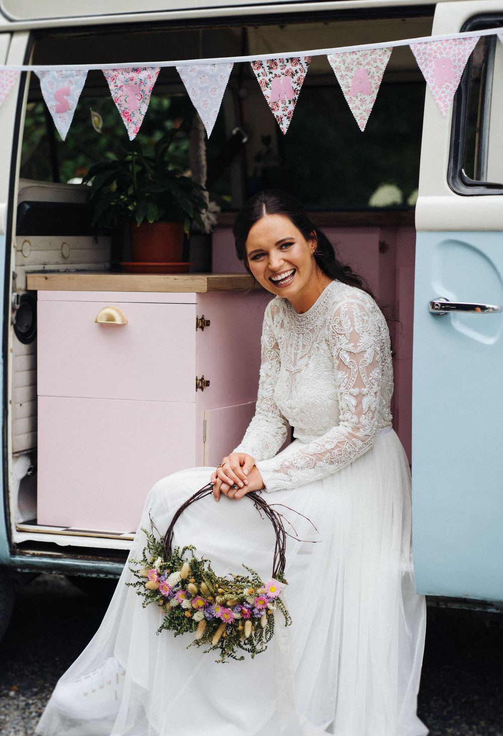 Elegant wedding scene featuring lace dress and floral basket in retro van setting.