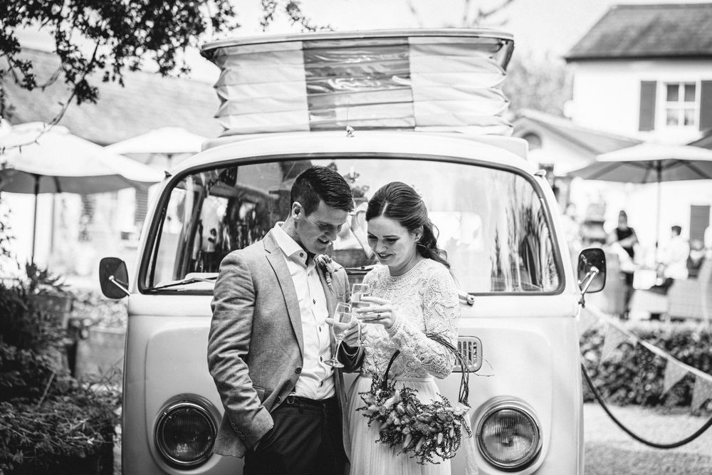 Black and white wedding photo with classic VW bus in background.